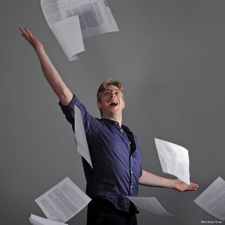 Portrait de Matthieu lançant des pages de textes avec un grand sourire